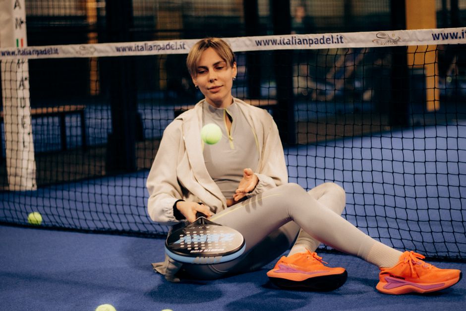 Dame in stijlvolle padeloutfit met rackets en accessoires op de baan.